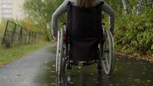 Woman with Spinal Cord Injury Moving Along Asphalt Road