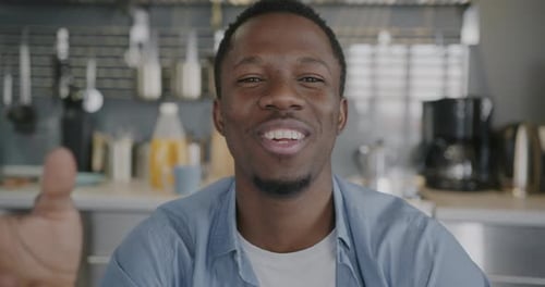 Smiling Man Waving in Modern Kitchen