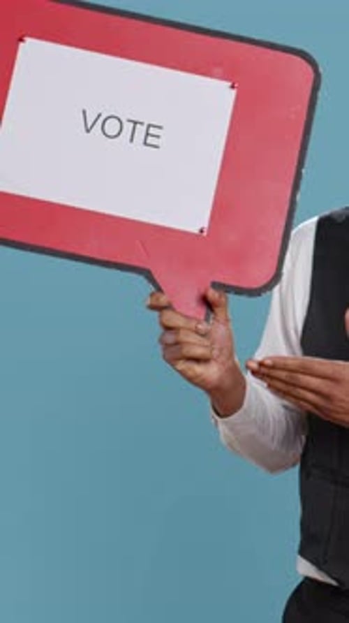 Person Holding Vote Sign on Blue Background