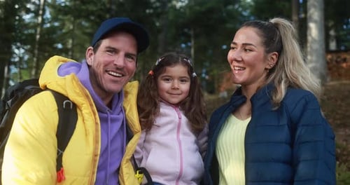 Happy young family having fun together into the woods during trekking day - Travel concept