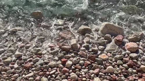 Crystal Clear Sea on a Sunny Day Water Flowing Between Round Sea Stones