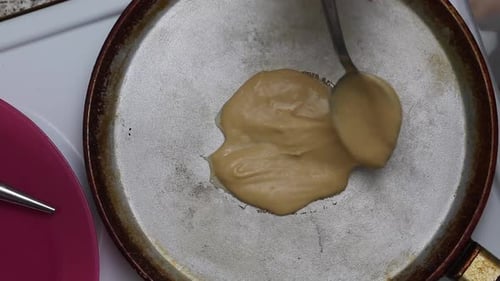 Die Frau legt den Teig auf eine heiße Bratpfanne. Waffelkegel vorbereiten. Nahaufnahme von oben.
