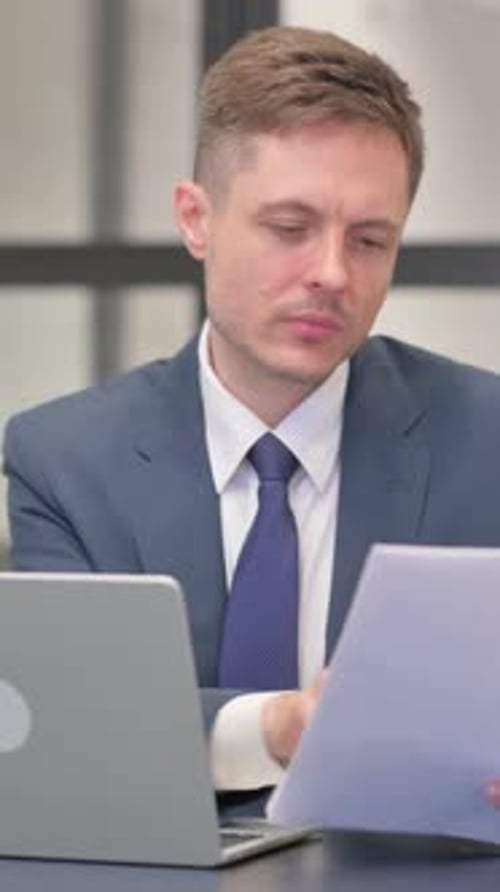 Serious Man in Suit Reads Documents at Desk