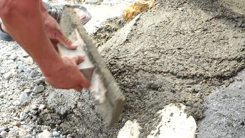 Construction Worker Hands Smooth Wet Cement in Wooden Frame at a Construction Site During Daytime to