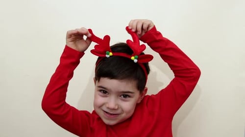 Smiling Child Wearing Reindeer Antlers Headband and Red Shirt