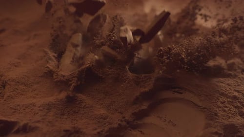 Chunks of Chocolate Falling on Cocoa Powder