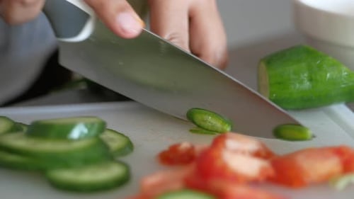 Young Man Cutting Cucumber on Chopping Board
