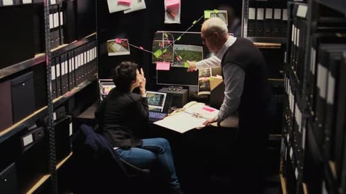 Woman and Man Discussing Investigation in Dark Workspace