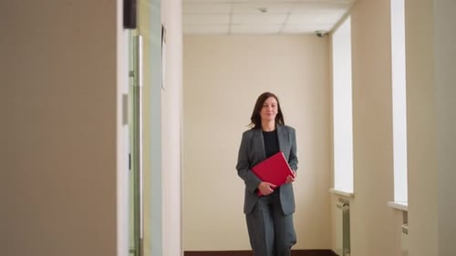 Blurred Businesswoman Walking Through Office Hallway Holding Red Folder