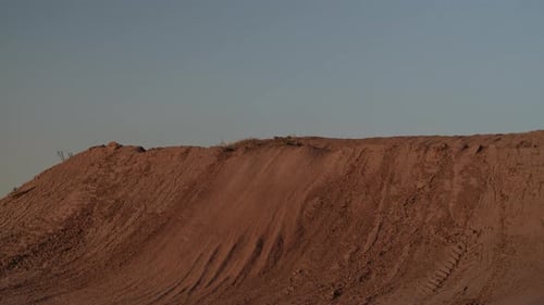 Dirt Bike Rider Jumping Over Sand Dune in Desert
