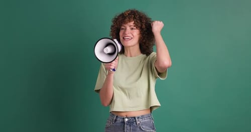 Excited Young Woman Screaming on Loudspeaker in Green Studio