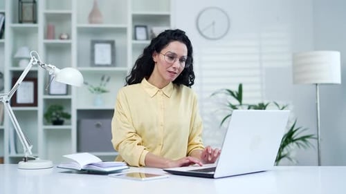 Young brunette businesswoman typing on laptop while sitting in home office. Female freelancer works