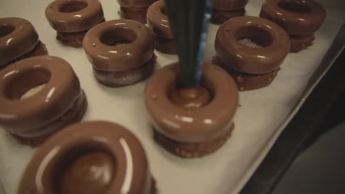 Decoration of delicious cakes with pastry syringe in bakery