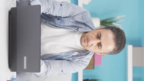 Vertical video of Man closing laptop with angry expression.