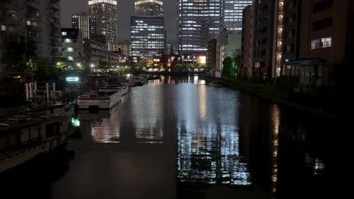 City canal at night with illuminated buildings and boats reflected on the water