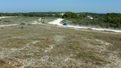 Blue Car Driving On Dusty Off-Road Track At Cape Kamenjak Near Pula, Croatia. - aerial