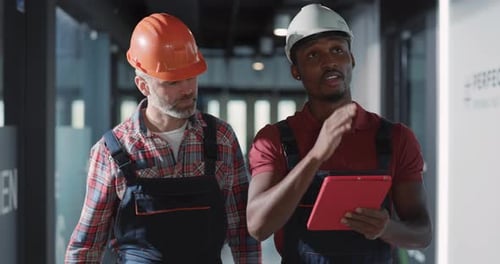 Bauarbeiter arbeiten mit einem Tablet gemeinsam an einem Projektplan, um die Effizienz zu steigern