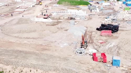 Vehículo excavador que prepara una tubería cilíndrica de concreto, vista aérea del desarrollo de viviendas constr
