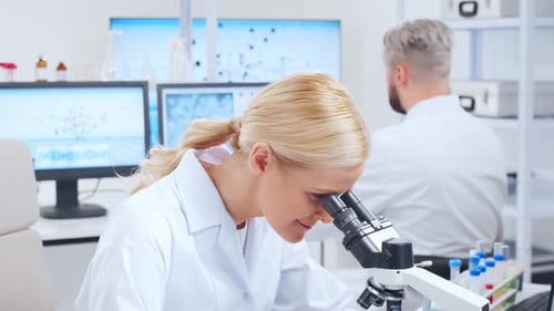 Woman Scientist Uses Microscope in Bright Laboratory
