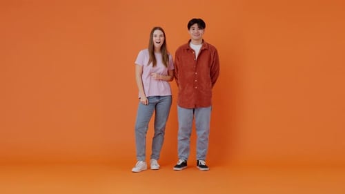 Smiling Asian Man and Woman Show Thumbs Up in Orange Room