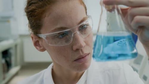 Female Scientist Examining Blue Liquid in Flask