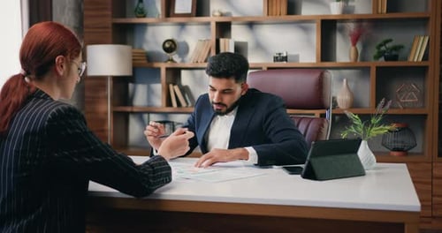 Two Business Multiracial Partners Discussing Documents in Office.