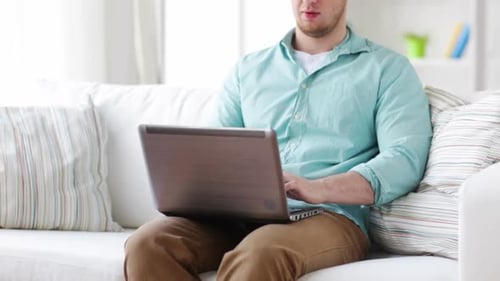 Man relaxing on couch using laptop computer