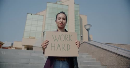Zeitlupenporträt einer Frau mit gemischten Rassen, die harte Arbeit hält, Schild mit motivierender und inspirierender Anstrengung