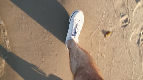Legs in White Sneakers Walking Along the Beach Topdown View at Sunset