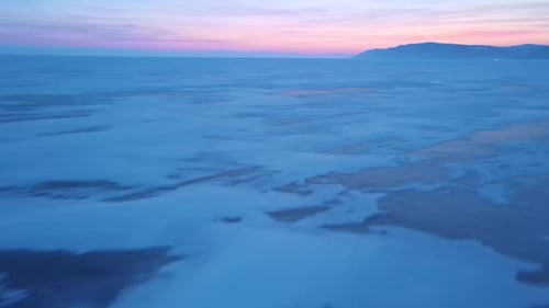 Enjoy the Tranquil Winter Landscape of a Frozen Lake at Sunset with Icy Reflections