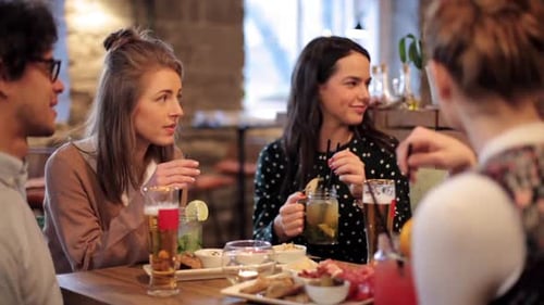 Happy multiethnic friends enjoy food and drinks at a cafe gathering indoors