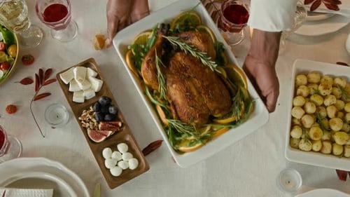Male Hands Putting Baked Turkey Flavoured with Citrus Slices on Festive Table