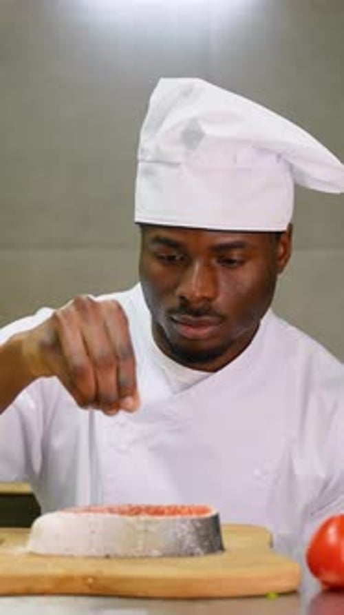 Chef Seasoning Salmon Fillet in a Kitchen
