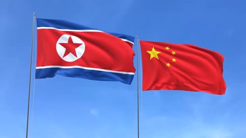 North Korea and China Flags Waving in Clear Sky
