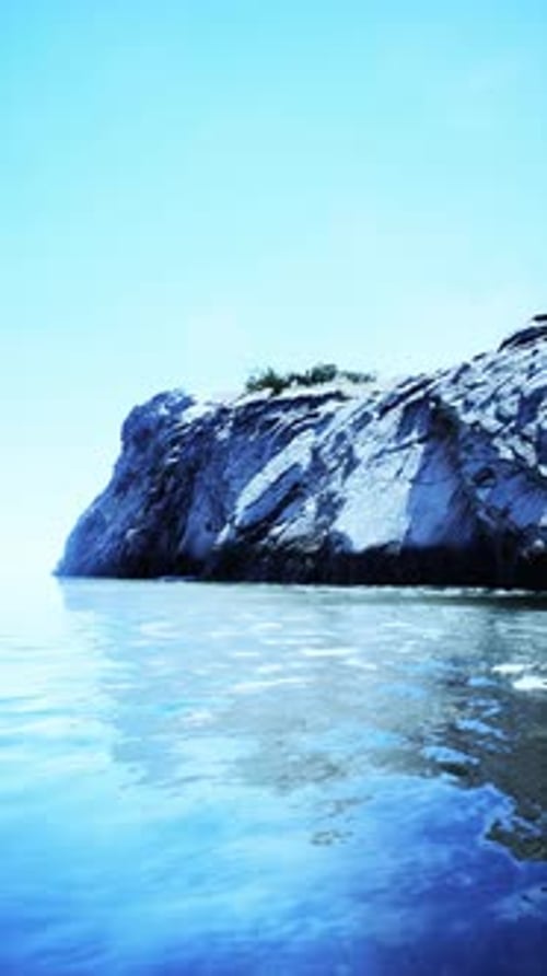 Vertical Video of Large Rock Island in the Middle of the Sea Water