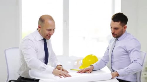 Smiling businessmen discuss blueprint project in bright modern office