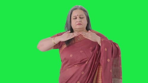 Relaxed Indian old woman doing breathe in breathe out exercise Green screen
