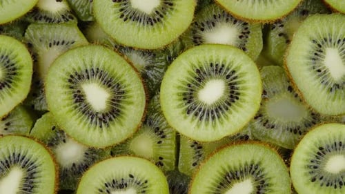 Green Kiwi Fruit Slices Slowly Rotating on Black Background