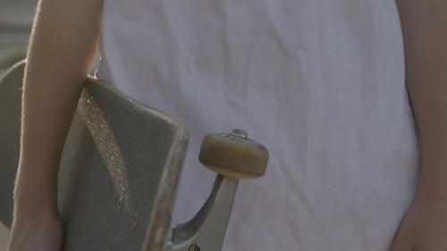 Person Holds Skateboard in Urban Setting Close Up
