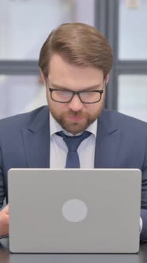 Man in Suit Cheers at Laptop in Office
