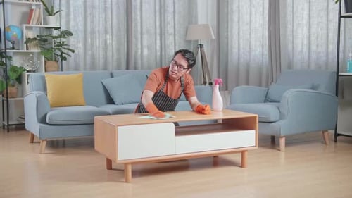 Man Cleaning Wooden Table in Living Room