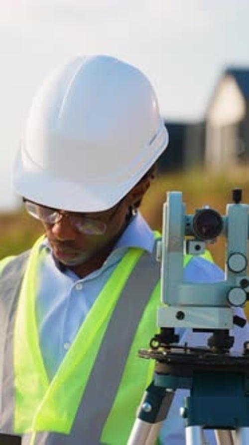 Professional Surveyor Operating Theodolite on Construction Site