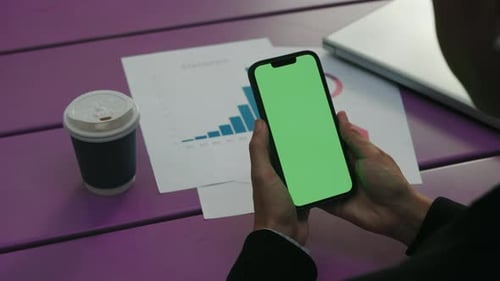 Closeup Green Screen Woman Holding Digital Smartphone in Hand on the Graphs and Work Table