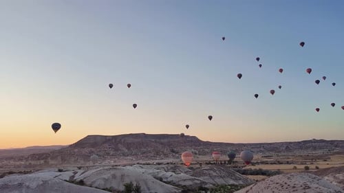 Expansive View of Dozens of Hot Air Balloons Rise at Dawn Over Cappadocia, Turkey