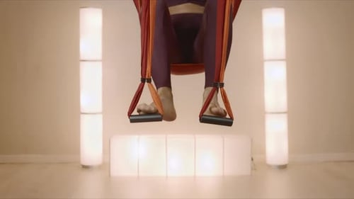 Flexible woman prepares for fly yoga training with straps at yoga studio