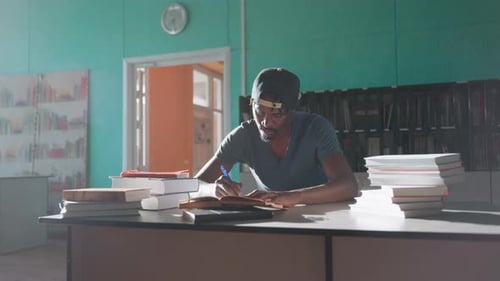 Joven estudiando intensamente y escribiendo en la biblioteca