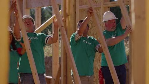 Volunteers building a house framework on a sunny day