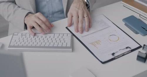 Closeup of Hands Businessperson Using Wireless Computer Keyboard and Reading Business Document at