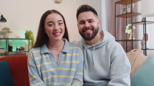 Happy Young Couple Talking to Camera at Home