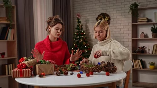 Women Crafting Christmas Wreaths Together in Festive Home